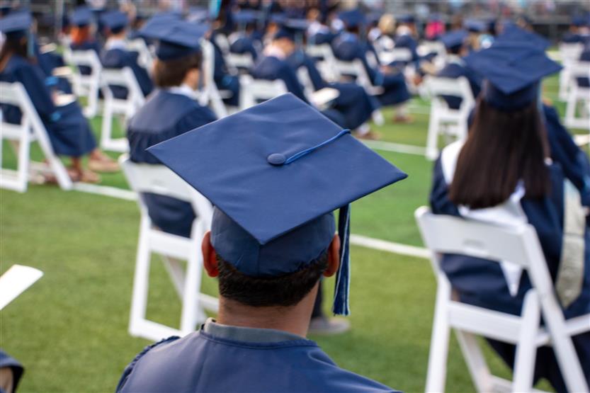 Students graduate outside on a football field